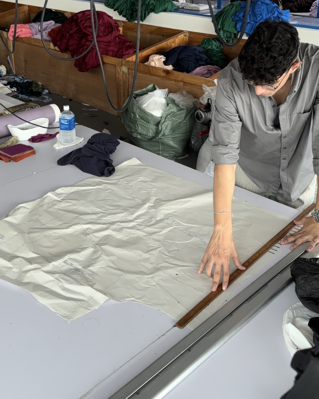 A paper pattern laid out on the cutting table in the factory, marked off against a wooden rule